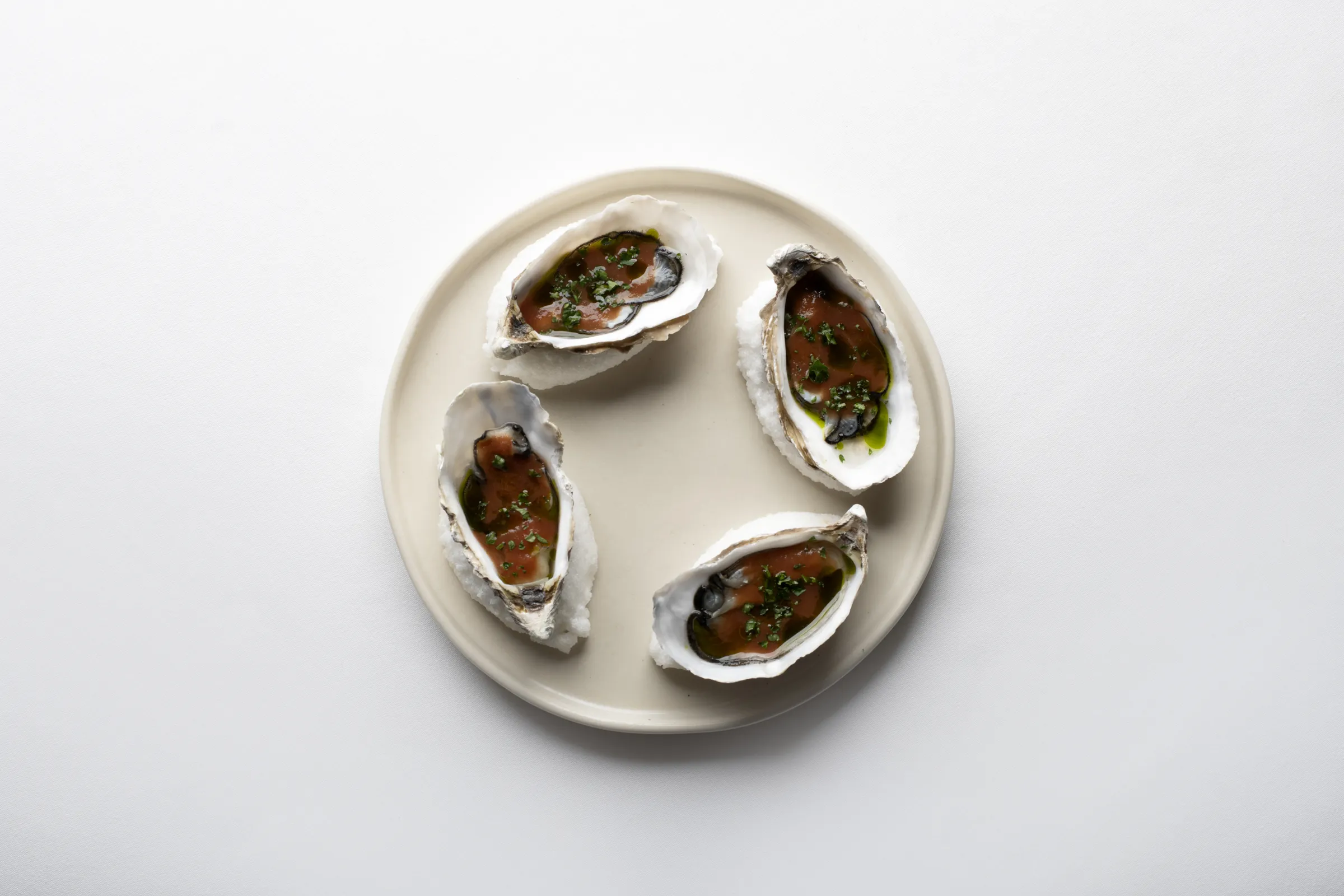 Four dressed oysters on a pale plate at Saskia's